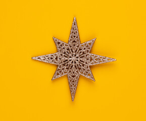 Christmas star decor on yellow colored background.