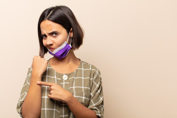 young hispanic woman looking impatient and angry, pointing at watch, asking for punctuality, wants...