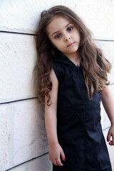 Fototapeta premium Portrait of Little cute girl leaning on white wall