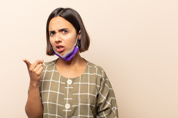 young hispanic woman pointing at camera with an angry aggressive expression looking like a furious,...