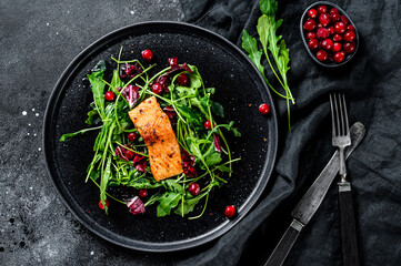 Seafood salad with trout, arugula, lettuce and cranberries. Black background. Top view