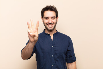 young handsome man smiling and looking friendly, showing number three or third with hand forward,...