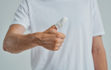 man in white t-shirt bandaged thumb health problems medicine