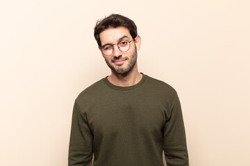 young handsome man looking happy and friendly, smiling and winking an eye at you with a positive...