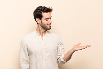 young handsome man feeling happy and smiling casually, looking to an object or concept held on the...