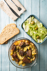 Top angle view on bowl with potatoes and meat ribs salad and bread on table