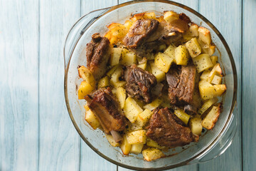 Top angle view on bowl with potatoes and meat ribs on table copy space