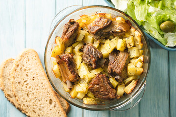 Top angle view on bowl with potatoes and meat ribs salad and bread on table
