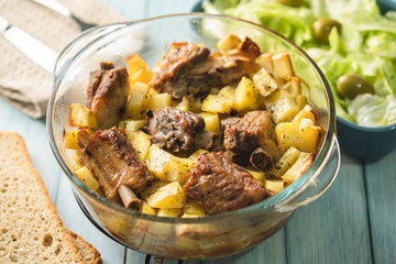 Top angle view on bowl with potatoes and meat ribs salad and bread on table