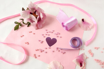 Heart among beads and ribbons with a peony flower on a pink background, top view-the concept of fun from needlework