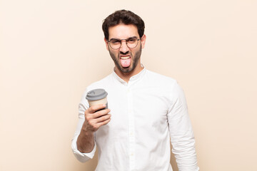 young handsome man feeling disgusted and irritated, sticking tongue out, disliking something nasty...