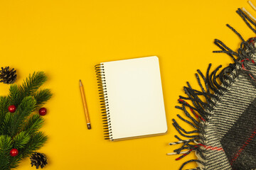 Winter workplace with notepad, warm and cozy plaid, copy space, top view, yellow background