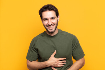 young handsome man laughing out loud at some hilarious joke, feeling happy and cheerful, having fun