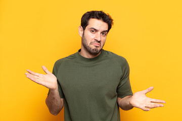 young handsome man looking puzzled, confused and stressed, wondering between different options,...