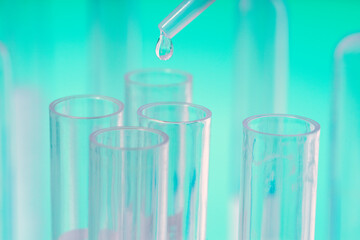 DROP OF LIQUID FALLING FROM THE PIPETTE INTO THE TEST TUBES IN THE LABORATORY. RESEARCH AND DEVELOPMENT. PROGRESS IN SCIENCE. CONCEPT OF VACCINE AGAINST CORONAVIRUS. MUTATION, VARIANT AND NEW STRAIN.