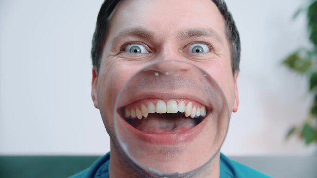A man with a magnifying glass shows his mouth, it turns out a funny and funny face.