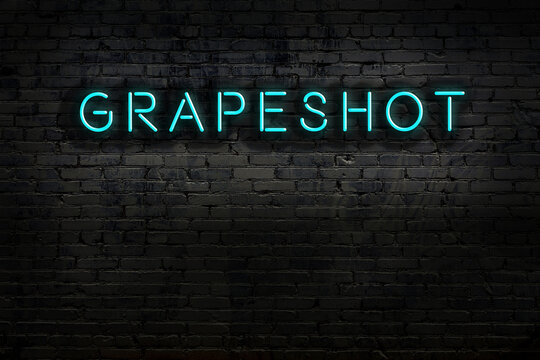 Neon sign. Word grapeshot against brick wall. Night view