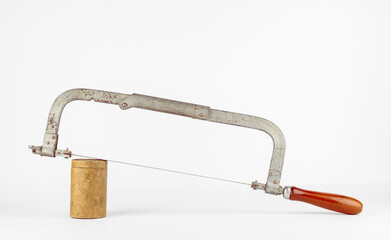 Vintage rusty coping saw placed on a round wooden block