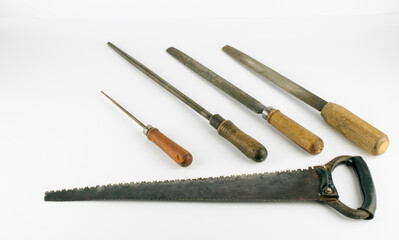 Vintage woodworking files and saw laying flat on a white background