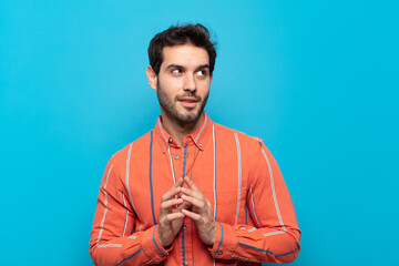 young handsome man feeling proud, mischievous and arrogant while scheming an evil plan or thinking...