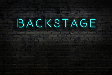 Night view of neon sign on brick wall with inscription backstage