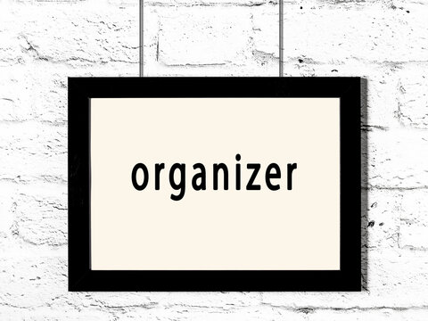Black frame hanging on white brick wall with inscription organizer