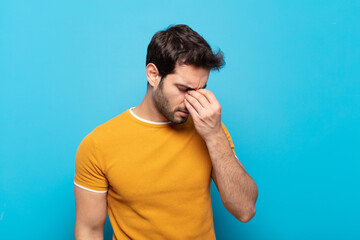 young handsome man feeling stressed, unhappy and frustrated, touching forehead and suffering...