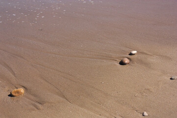 Stones in the sand on the beach near the sea waves