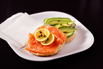 Bagel with lox, capers and sliced avocado with copy space
