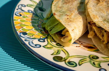 Exquisite traditional quesadillas with chicken and spinach inside, on a plate on a blue table in...