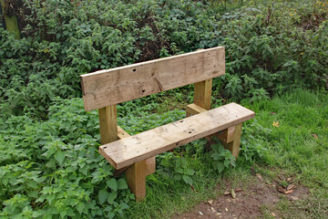 A basic timber bench set beside the canal towpath, for weary walkers to take a rest