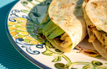 Exquisite traditional quesadillas with chicken and spinach inside, on a plate on a blue table in...