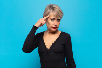 middle age woman feeling confused and puzzled, showing you are insane, crazy or out of your mind