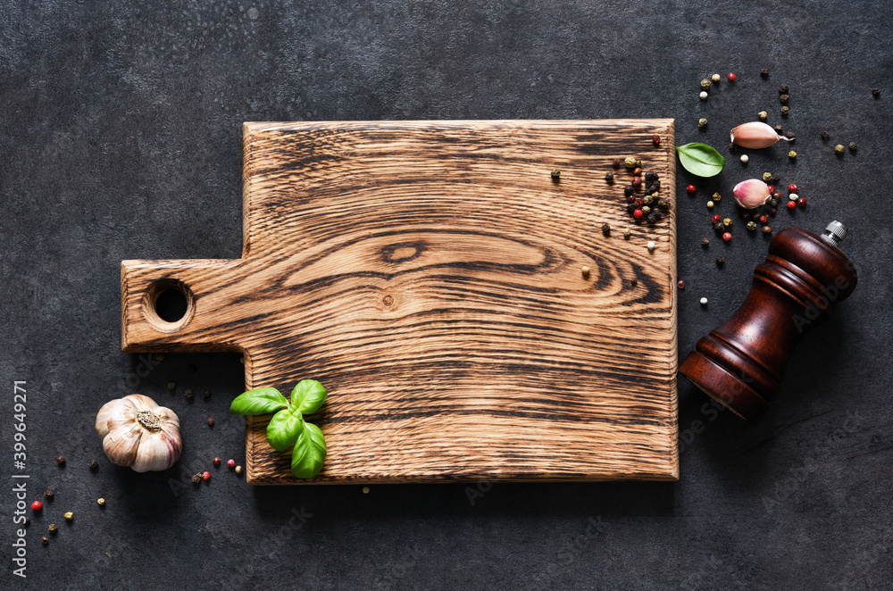 Wall mural cutting board with fresh basil and spices on a black concrete table. top view with copy space.