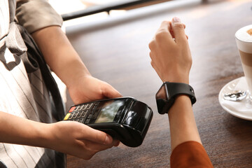 Woman making payment with smart watch in cafe, closeup