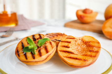Delicious grilled peaches with mint on plate, closeup