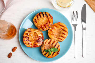 Delicious grilled peaches with honey and mint on white table, flat lay