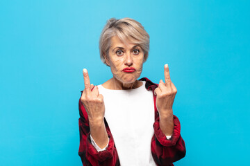 middle age woman feeling provocative, aggressive and obscene, flipping the middle finger, with a rebellious attitude