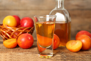 Delicious plum liquor and ripe fruits on wooden table. Homemade strong alcoholic beverage