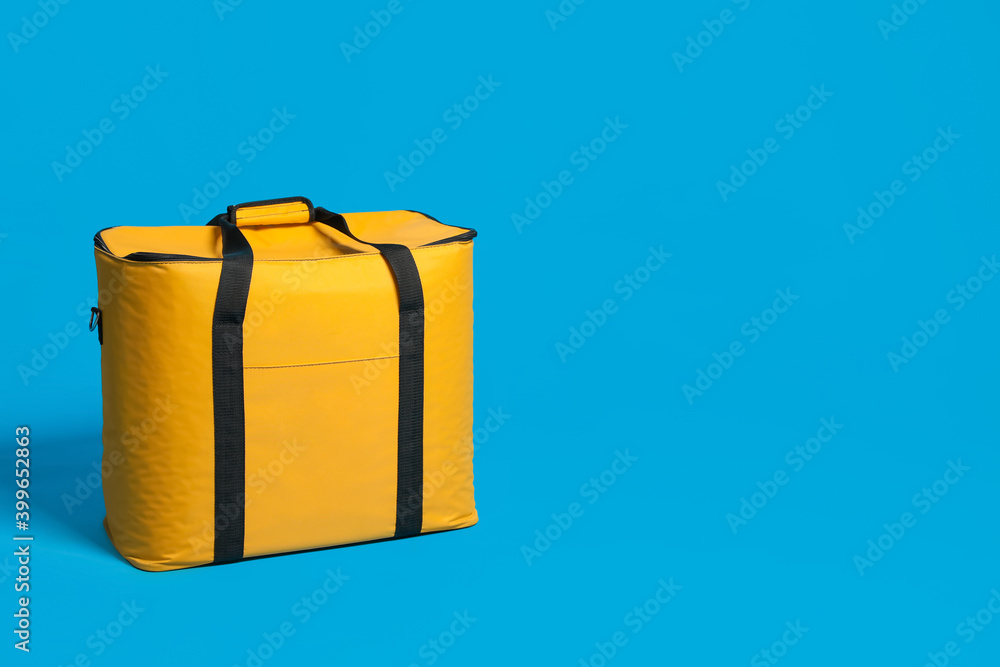 Poster Modern yellow thermo bag on light blue background. Space for text