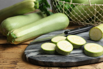 Sliced zucchini and grey marble board on wooden table, closeup