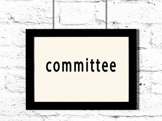 Black frame hanging on white brick wall with inscription committee - obrazy, fototapety, plakaty