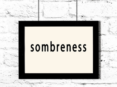 Black frame hanging on white brick wall with inscription sombreness
