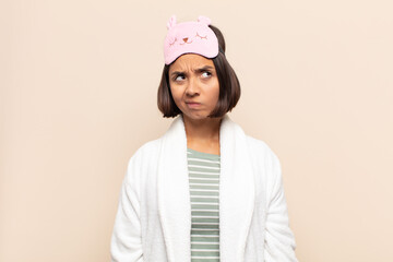 young latin woman looking puzzled and confused, wondering or trying to solve a problem or thinking