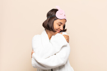 young latin woman feeling in love, smiling, cuddling and hugging self, staying single, being...