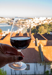 Tasting of different fortified dessert ruby, tawny port wines in glasses with view on Douro river, porto lodges of Vila Nova de Gaia and city of Porto, Portugal