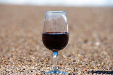 Tasting of different fortified dessert ruby, tawny port wines in glasses on sandy beach with view on waves of Atlantic ocean near Vila Nova de Gaia and city of Porto, Portugal