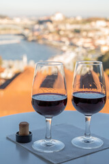 Tasting of different fortified dessert ruby, tawny port wines in glasses with view on Douro river, porto lodges of Vila Nova de Gaia and city of Porto, Portugal