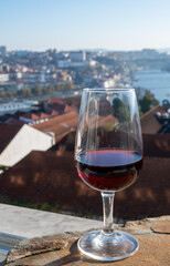 Tasting of different fortified dessert ruby, tawny port wines in glasses with view on Douro river, porto lodges of Vila Nova de Gaia and city of Porto, Portugal