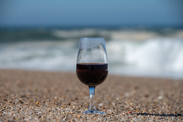 Tasting of different fortified dessert ruby, tawny port wines in glasses on sandy beach with view on waves of Atlantic ocean near Vila Nova de Gaia and city of Porto, Portugal
